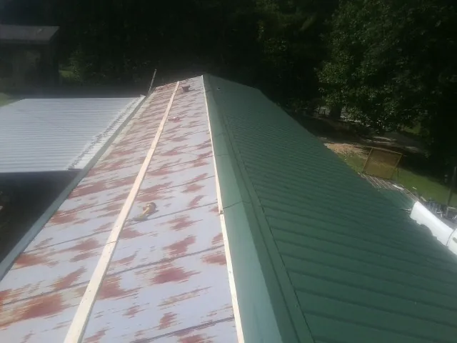 Old rusted panels beside newly installed green metal roofing — Wind Damage Roof Repair by Roofing Brothers in Plover