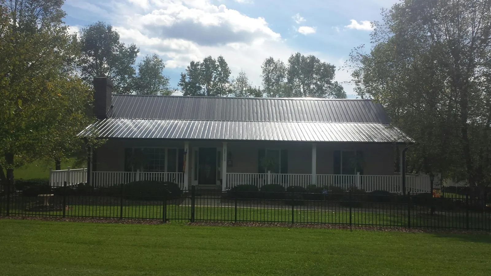 Gray metal roof on a brick ranch with a full width front porch — Gutter Guard Installation work by our crew in Plover