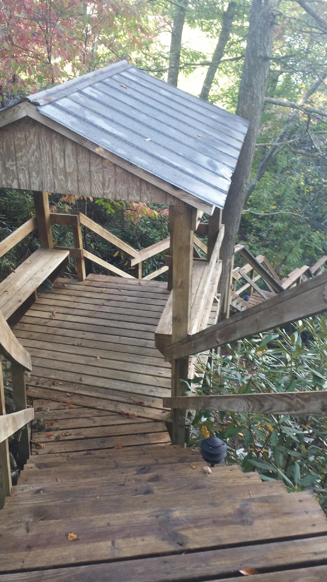Metal roofed shelter over wooden steps on a wooded walkway — Skylight Repair & Installation work by our crew in Plover