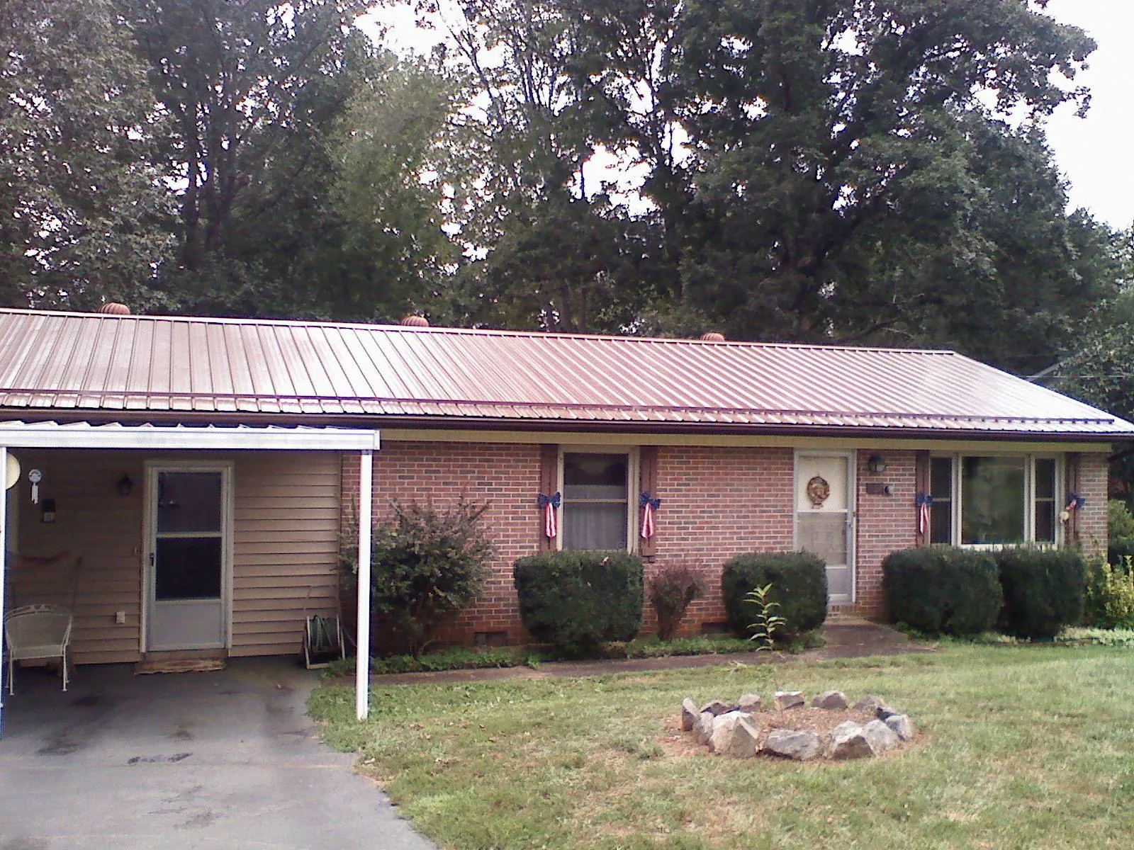 Bronze metal roof and carport on a brick ranch home — Roof Repair work by our crew in Plover